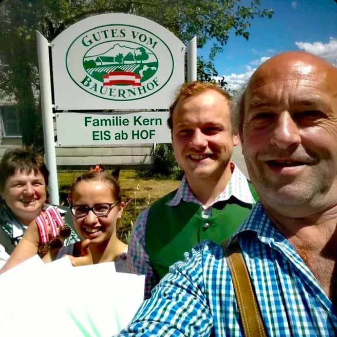 A family outside in front of their farm's logo.