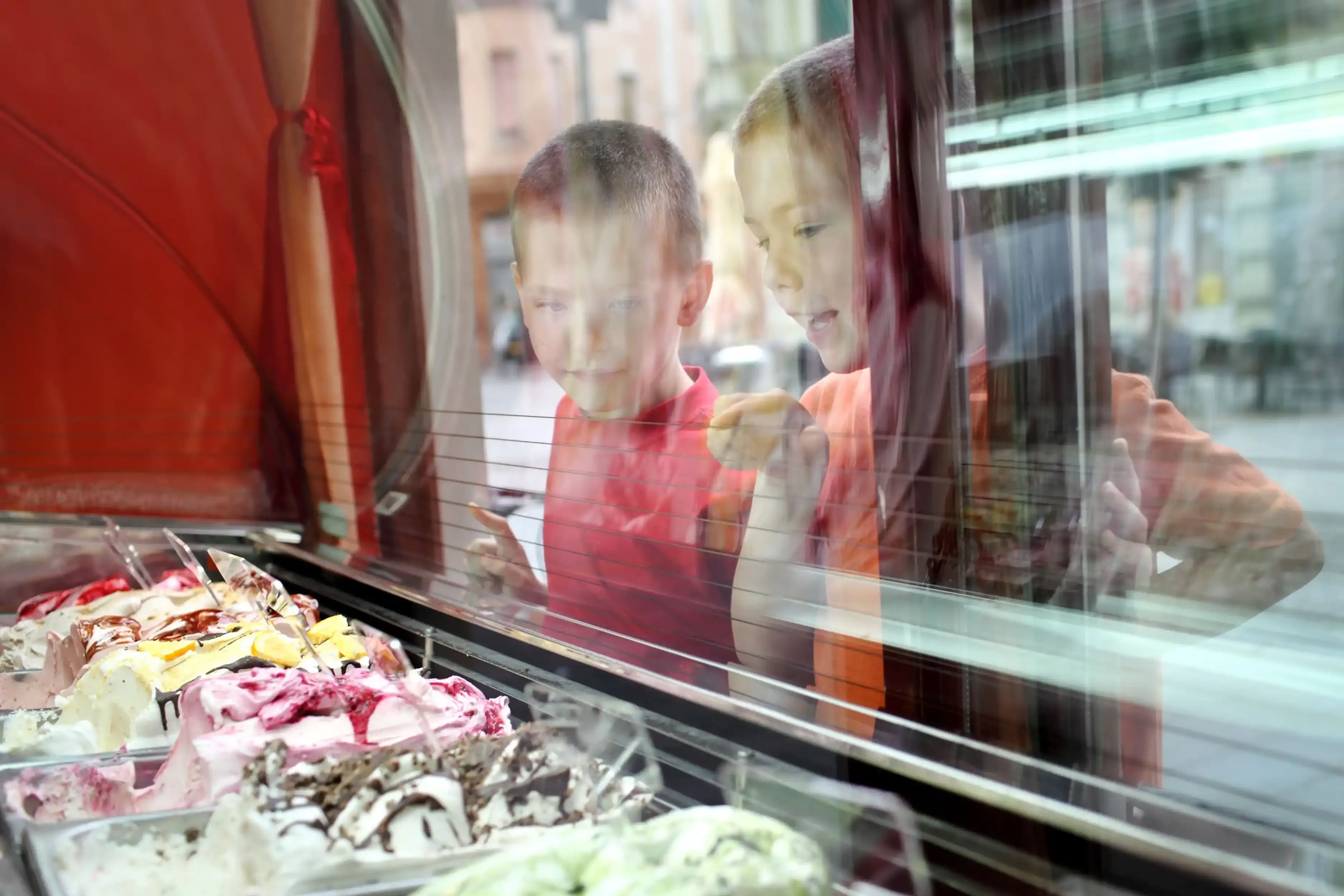 Two kids looking at a display of delicious ice cream.